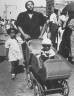 Morris Engel / Family walking down street with buggy / ca. 1935