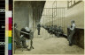 Tappan Adney / Prison cell block, man playing organ, prisoners sitting on bench behind gate / 1890