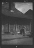 Arnold Genthe / Woman holding a sack standing by the doorway of a building in the French Quarter, New Orleans / between 1920 and 1926