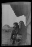 Arnold Genthe / Two Ainu women standing outside by the wall of a wooden hut / 1908