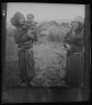 Arnold Genthe / Two Ainu woman, one holding a child, standing outside / 1908