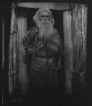 Arnold Genthe / Ainu man holding a staff standing at the doorway of a hut / 1908