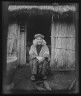 Arnold Genthe / Ainu woman seated in front of the doorway of a hut / 1908