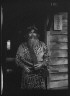 Arnold Genthe / Ainu chief wearing a headdress and holding a sword standing in a doorway / 1908