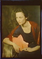 Seated woman wearing a black short-sleeved dress with a red shawl or wrap