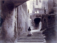 Northern Italy [woman coming down steps, series of archways]